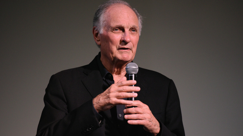 Alan Alda speaking black suit mic