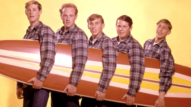 The Beach Boys posing with a surf board