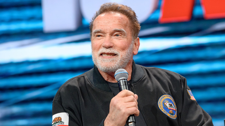 Arnold Schwarzenegger beard seated speaking microphone