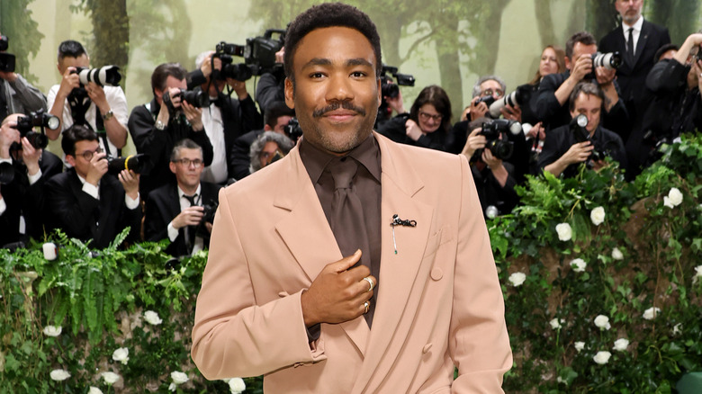 Donald Glover smiling tan suit photographers behind