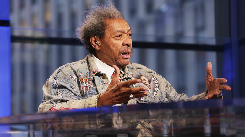 Don King gesturing while speaking at a podium