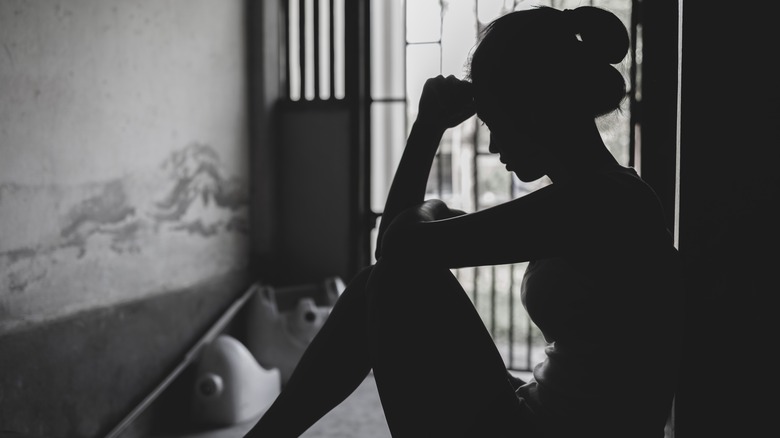 Silhouette of a woman being held in a small apartment