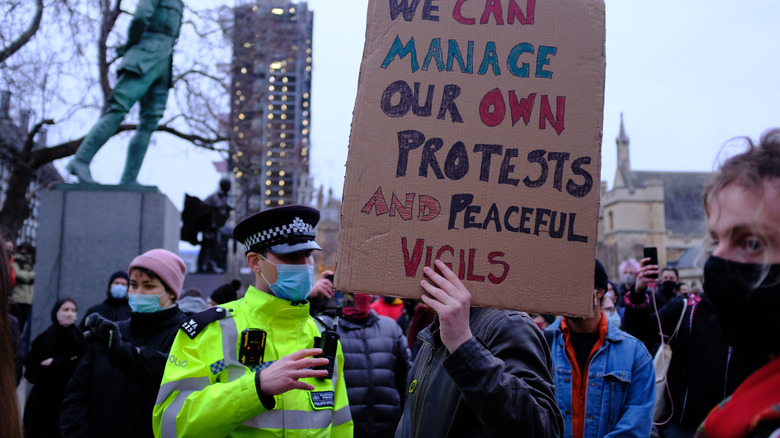 Police with protestor holding a sign