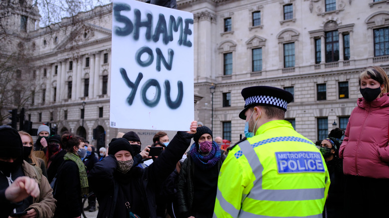 Police officer and protesters holding a sign