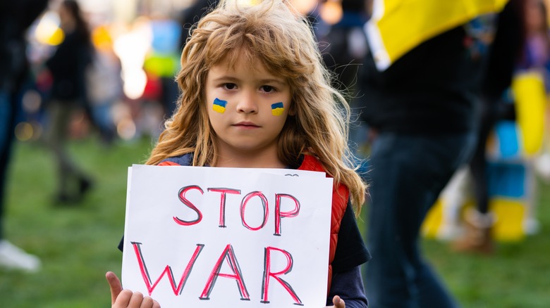 Refugee child holding "stop war" sign