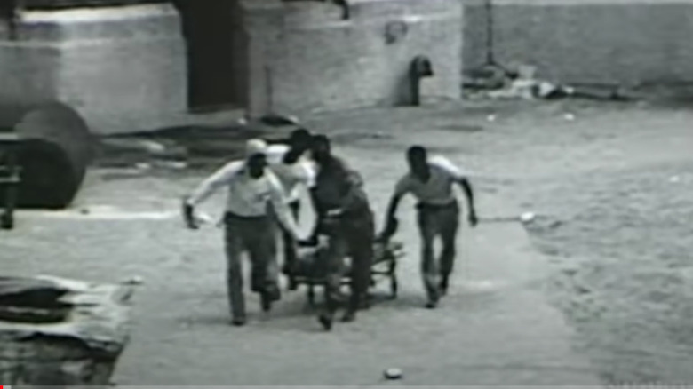 Inmates Carry a Body On a Stretcher