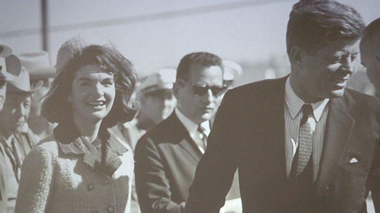 John and Jackie Kennedy smiling in crowd suited