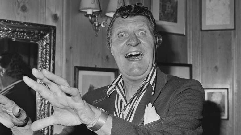 Tommy Cooper smiling suit hands raises