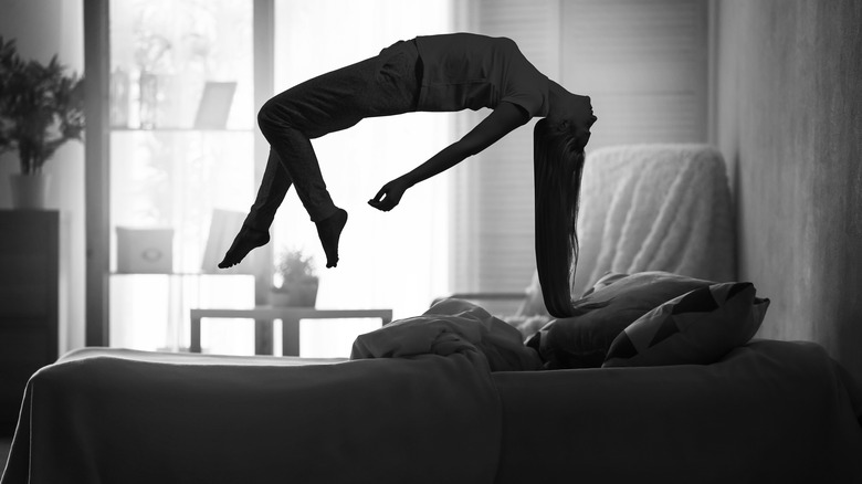 long-haired woman floating over bed