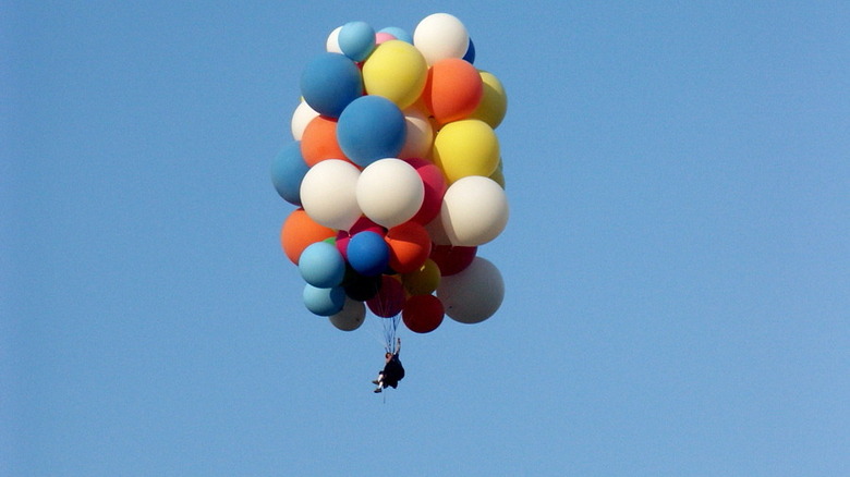 man floating under balloons