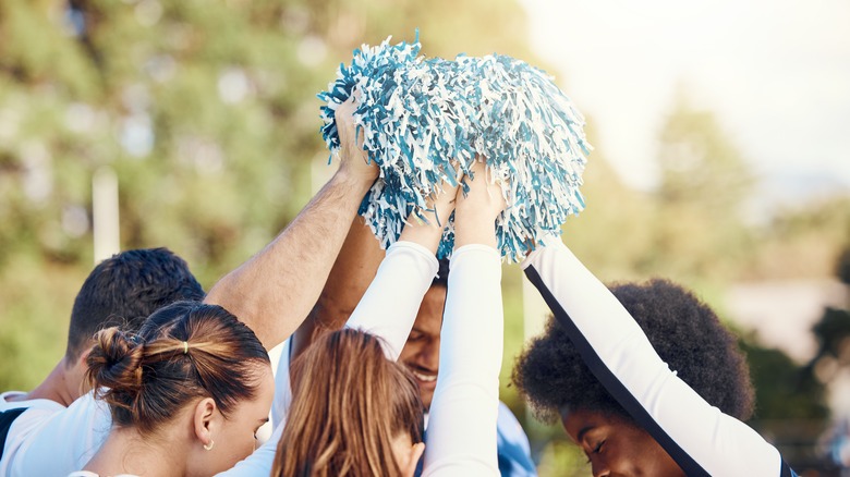 Cheerleaders huddle arms in air