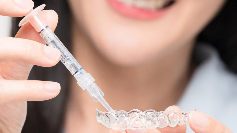 Woman applies whitening gel to tray