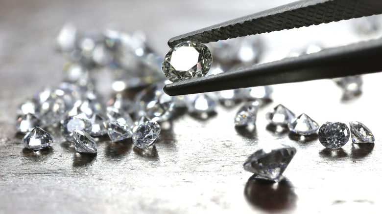 A diamond held between tweezers.