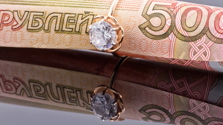 A diamond ring sitting on a dollar bill.