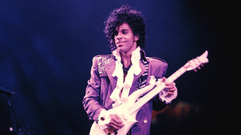 Prince purple suit playing guitar on stage