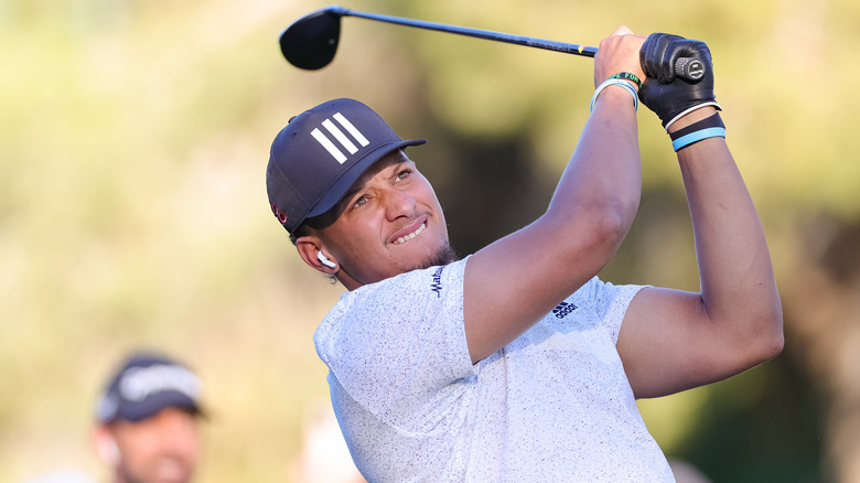 Patrick Mahomes biting his lip after taking a golf swing