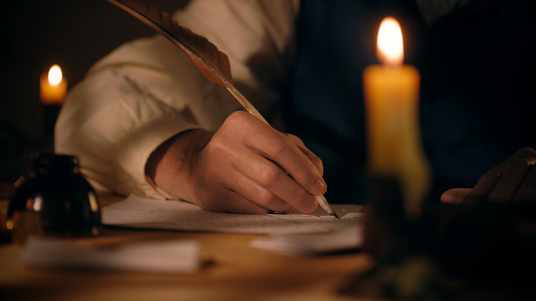 a hand writing on parchment with a quill