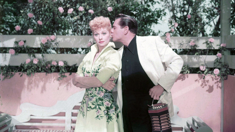 Desi Arnaz kissing Lucille Ball flowers background