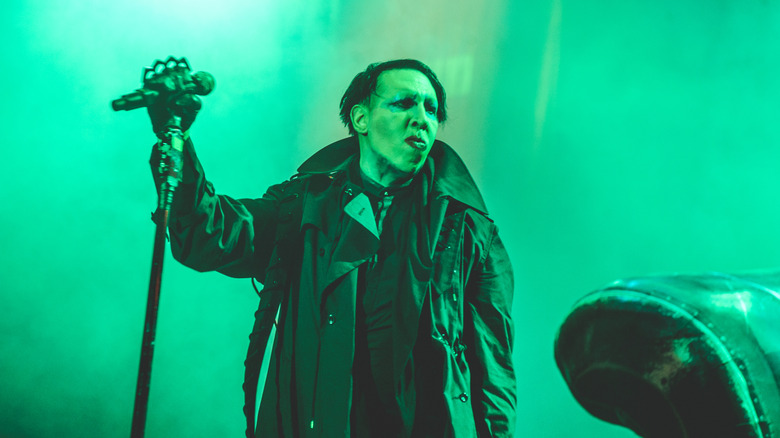 Marilyn Manson in large coat onstage with microphone