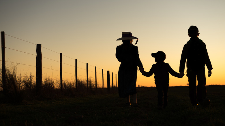 Mennonite children holding hands sunset fence