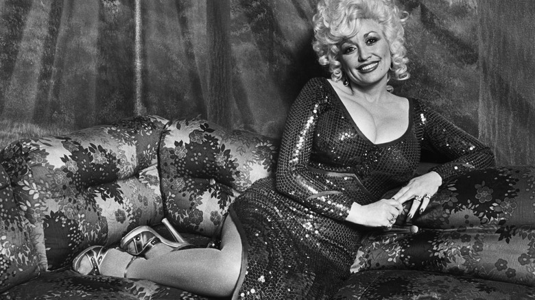 Dolly Parton on a sofa in a sequined dress