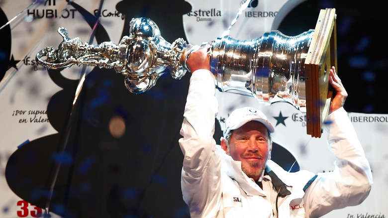 Larry Ellison holding up a massive trophy