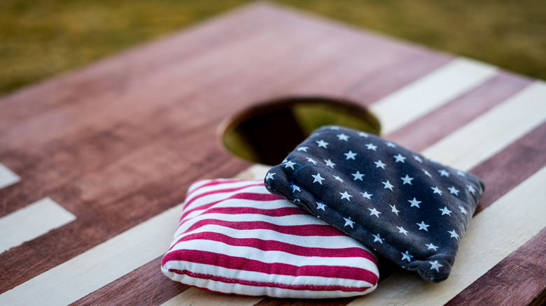 Two bags lying on a cornhole board