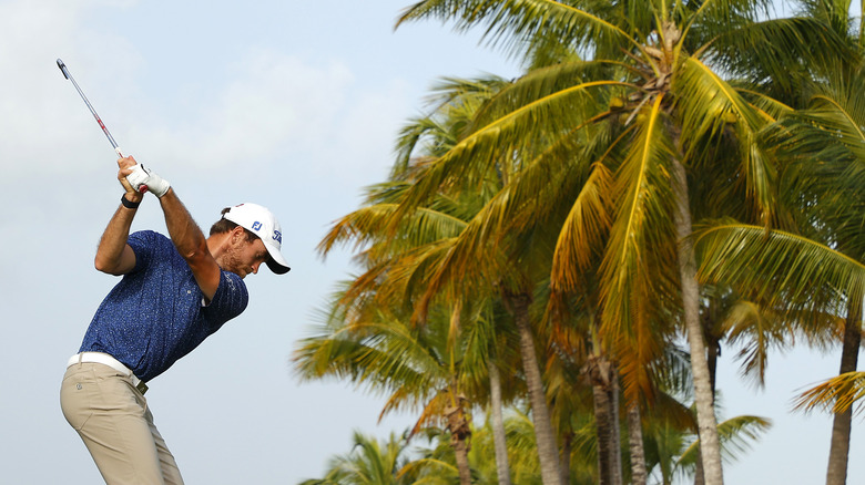 Justin Doeden teeing off with palm trees in background