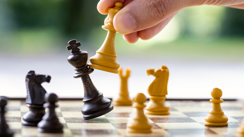 A chess player knocking over a king on a chessboard