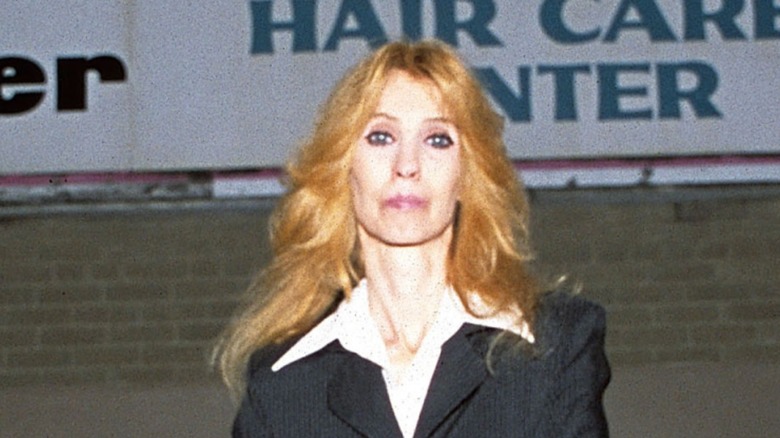 debbie nelson stands outside of a hair salon in a suit