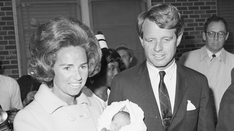 Young Ethel Kennedy carrying baby