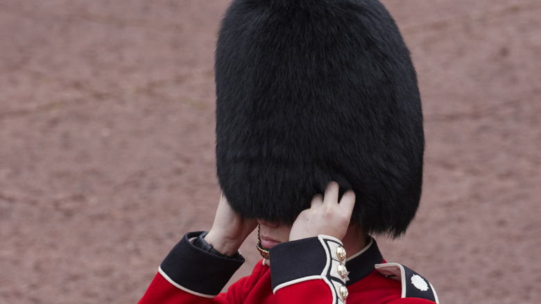 A Coldstream guard adjusts his bearskin on head