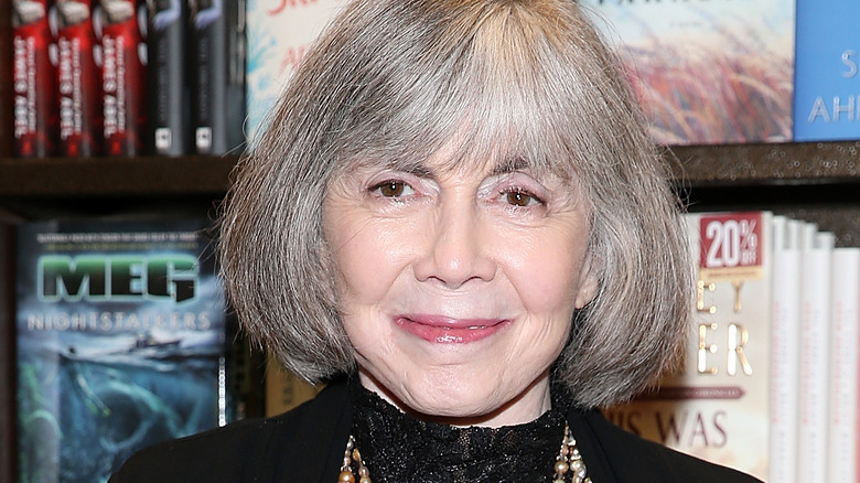 Anne Rice smirking in front of books