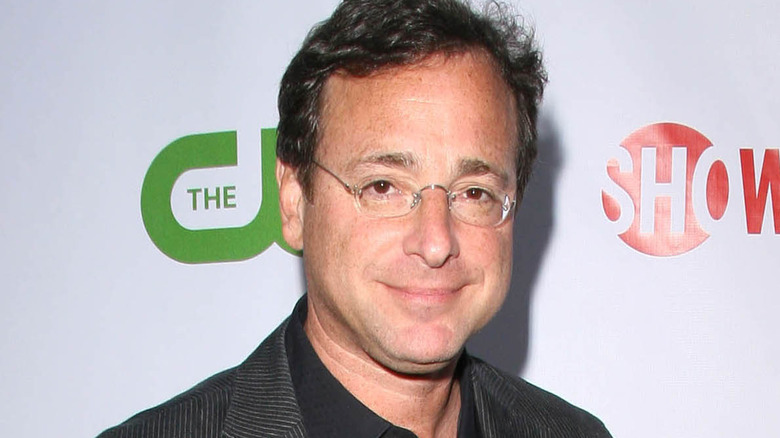 Bob Saget smirking in reading glasses