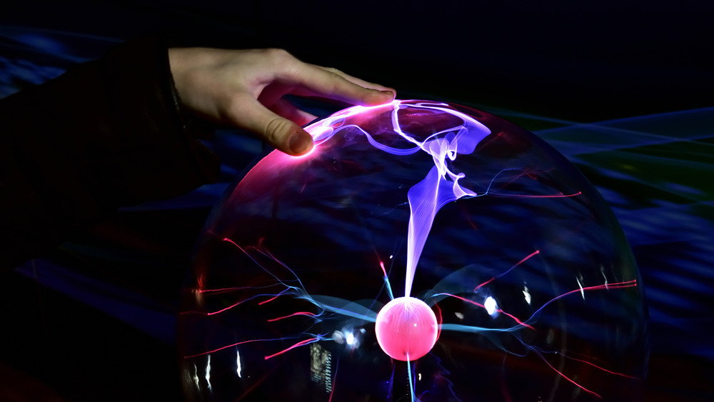 A man's finger touching a tesla coil