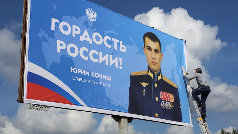 Worker adjusts propaganda poster