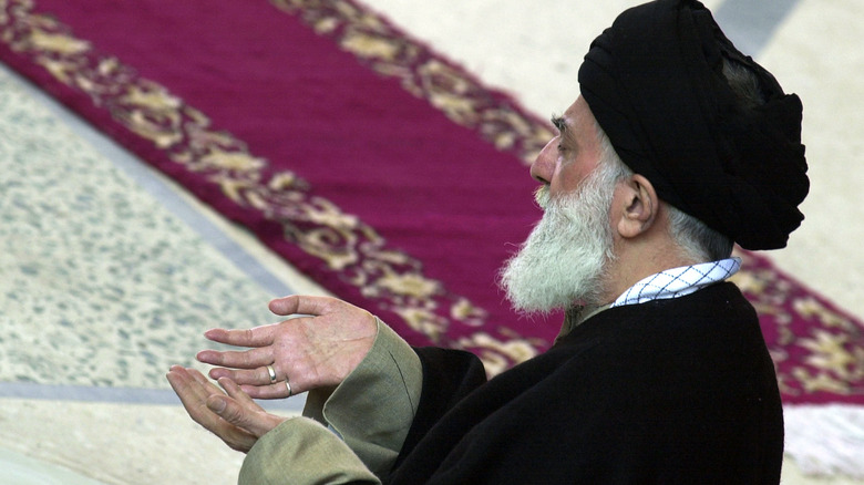 Ali Khamenei leads prayers in front of a rich rug