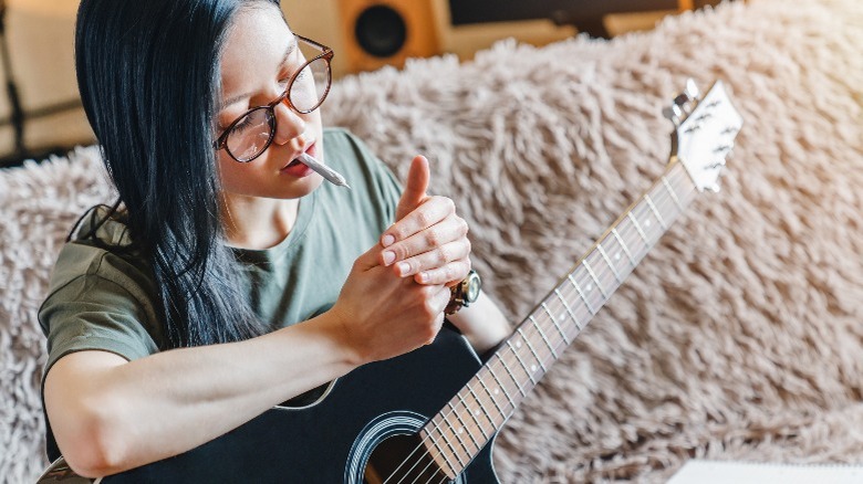 Woman blue hair smoking joint holding guitar