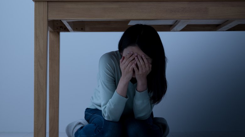 girl hiding under desk