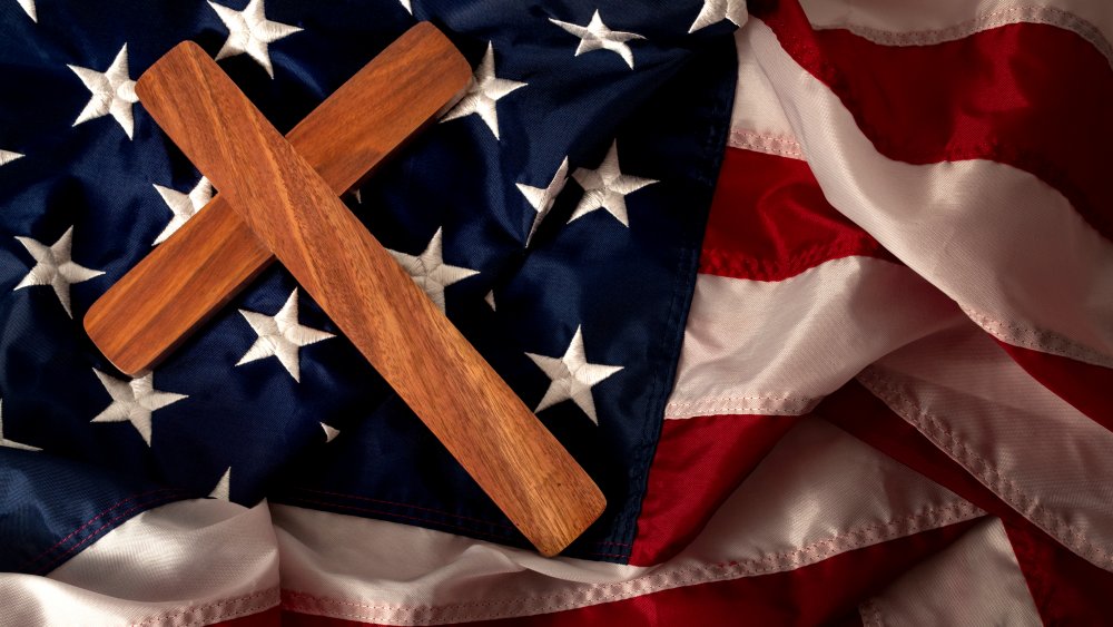 Plain wooden cross against an American flag