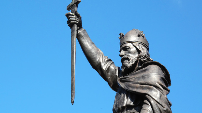 A statue of Alfred the Great holding a sword aloft against blue sky