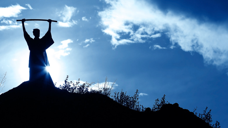 man on hill with staff