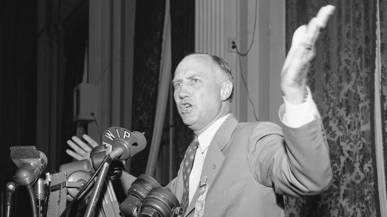 Strom Thurmond arms raised suit talking mics