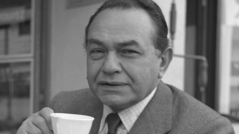 Edward G. Robinson holding cup squinting