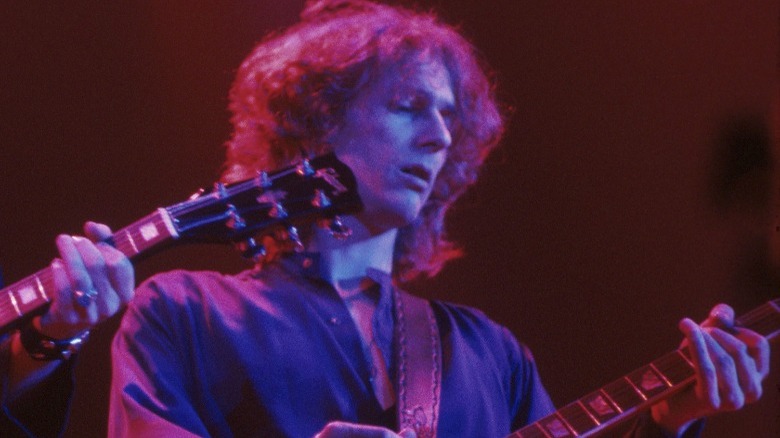 Allen Lanier playing guitar onstage under red lights