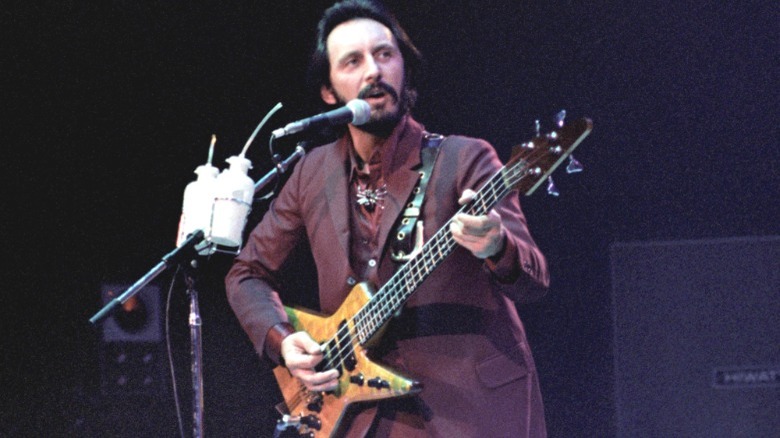 John Entwistle playing bass onstage in a maroon suit