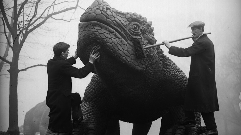 Workers clean dinosaur statue