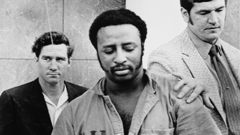 Frank Matthews in a prison uniform being escorted by guards