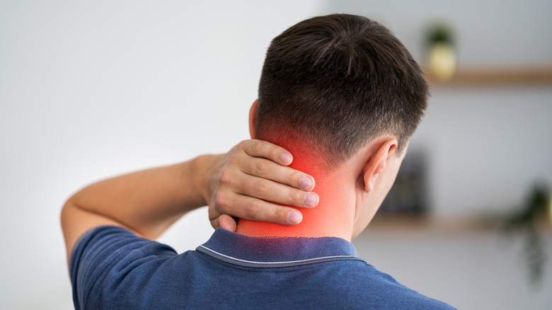 Young man rubbing his aching neck