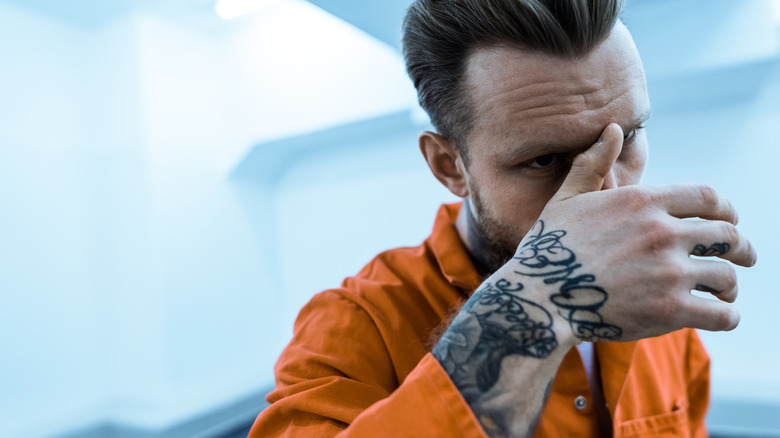 Tattooed prisoner covering face